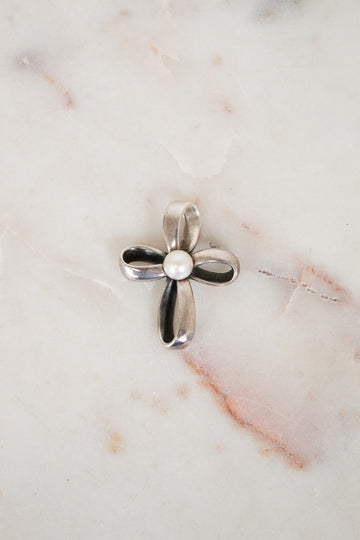 Silver cross pendant on a marble surface
