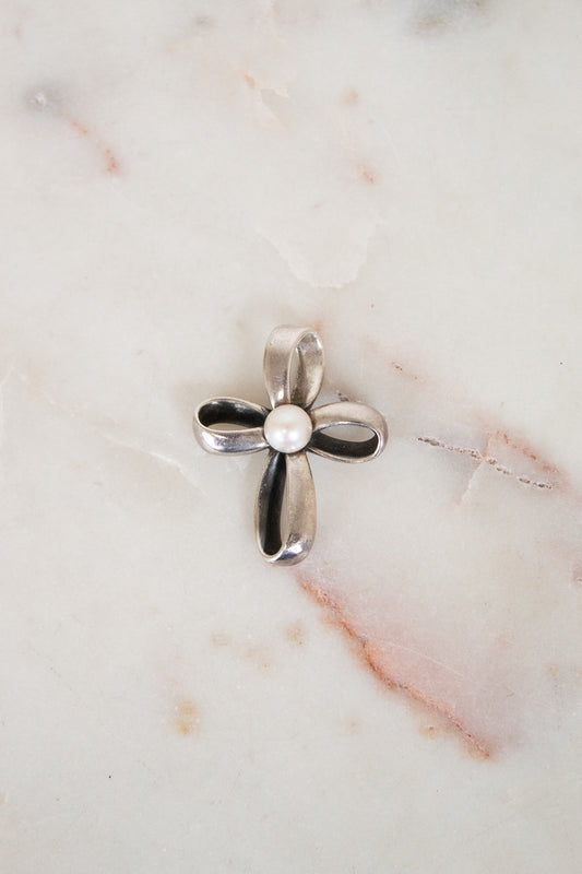 Silver cross pendant on a marble surface