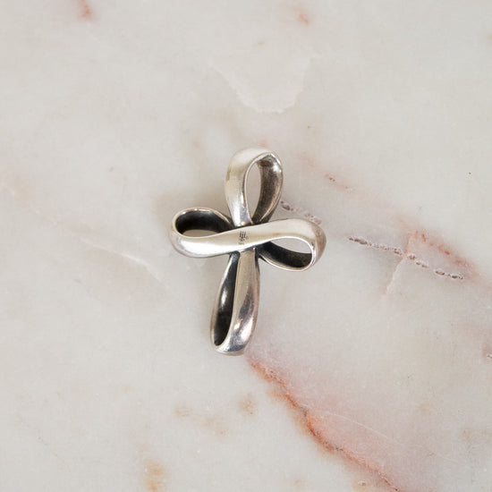 Silver cross pendant on a marble surface