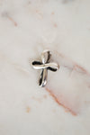 Silver cross pendant on a marble surface