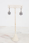 Snowflake earrings on a stand with a white background