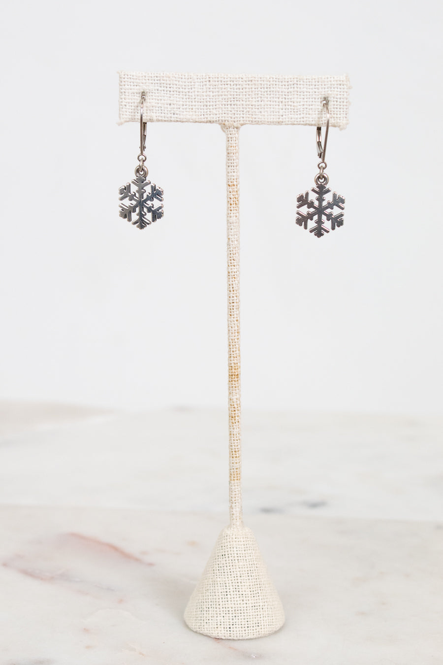 Snowflake earrings on a stand with a white background