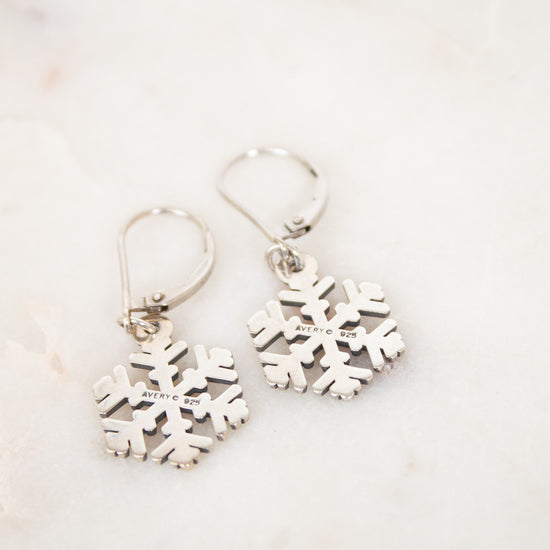 Silver snowflake earrings on a light marble background
