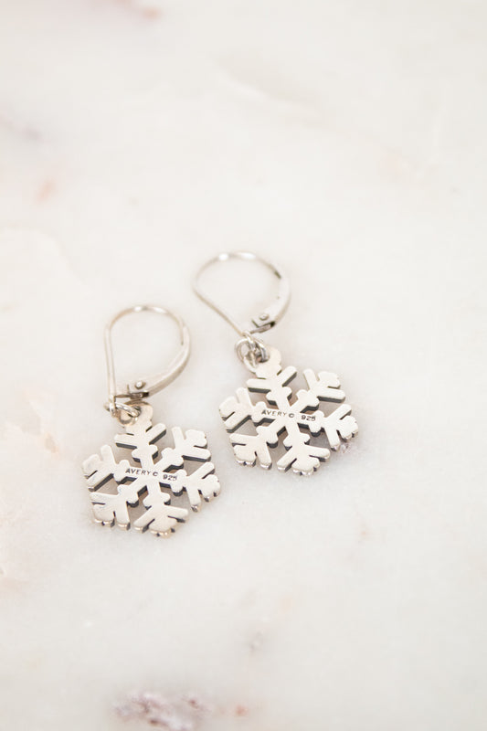Silver snowflake earrings on a light marble background