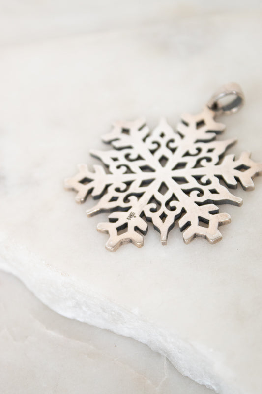 Silver snowflake pendant on a light background