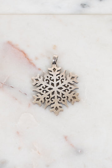Silver snowflake pendant on a marble surface