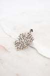 Silver snowflake-shaped pendant on a white background