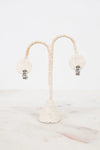 Pair of earrings on a decorative stand with a white background