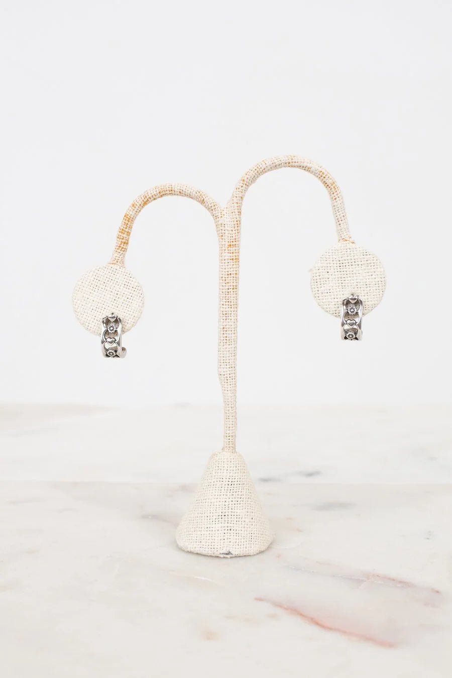 Pair of earrings on a decorative stand with a white background