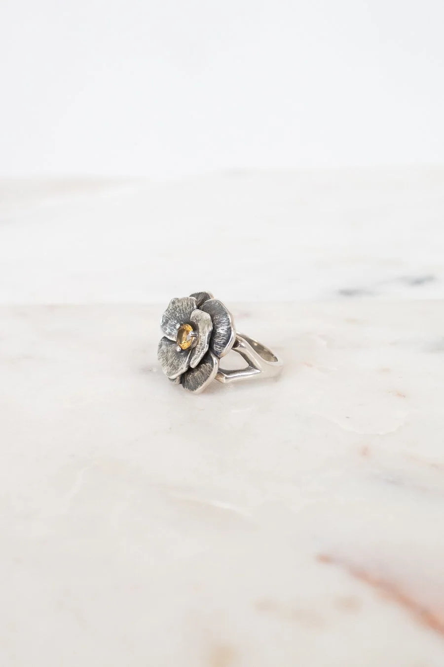 Silver flower-shaped ring on a marble surface