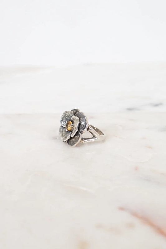 Silver flower-shaped ring on a marble surface