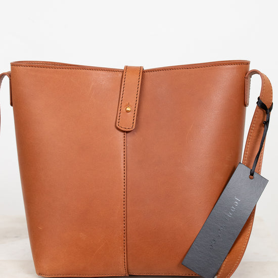 Brown leather handbag with a tag on a light background
