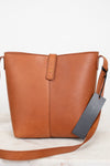 Brown leather handbag with a tag on a light background