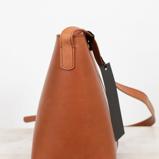 Brown leather handbag with a tag on a light background