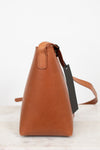 Brown leather handbag with a tag on a light background