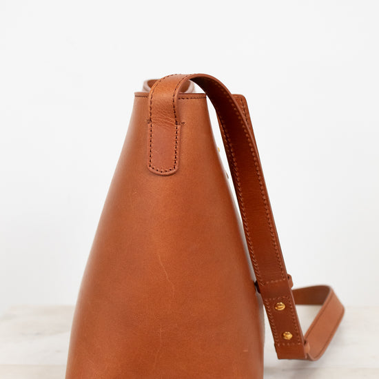 Brown leather handbag with a strap on a light background
