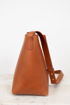 Brown leather handbag with a strap on a light background