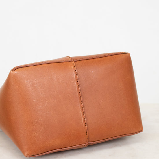 Bottom of brown leather bag on a white marble surface