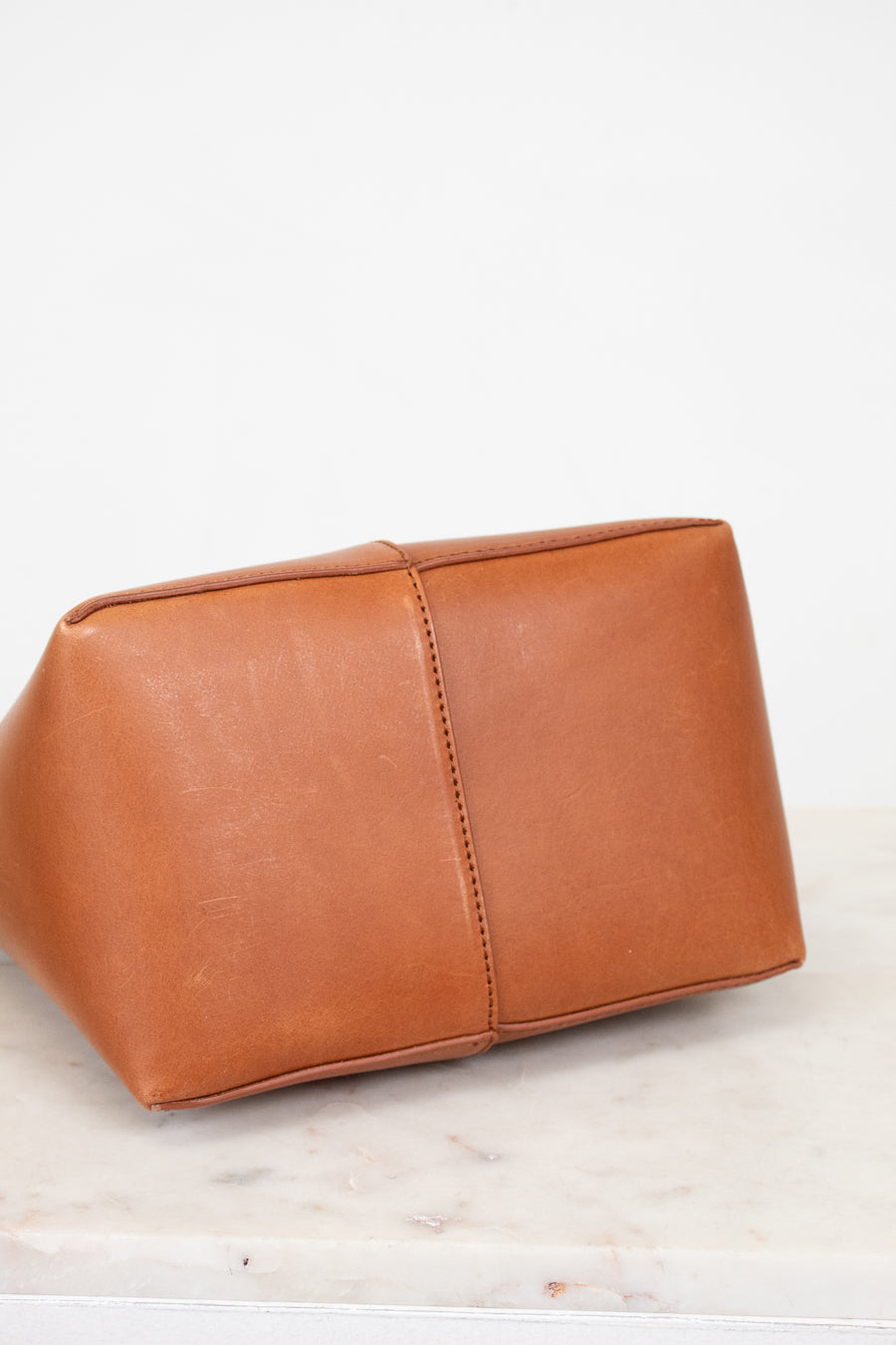 Bottom of brown leather bag on a white marble surface