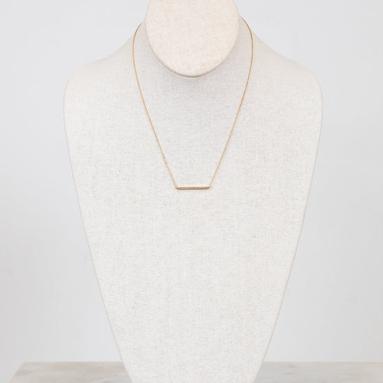 Gold necklace on a white mannequin bust against a white background