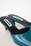 Teal high-heeled shoe with black sole on a white background