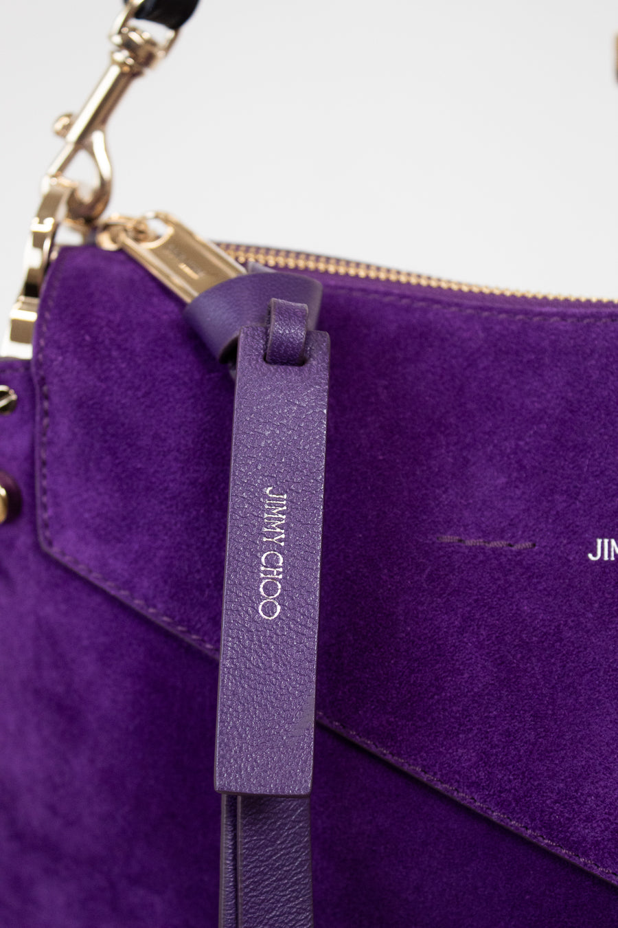 Purple handbag with a visible brand tag on a light gray background