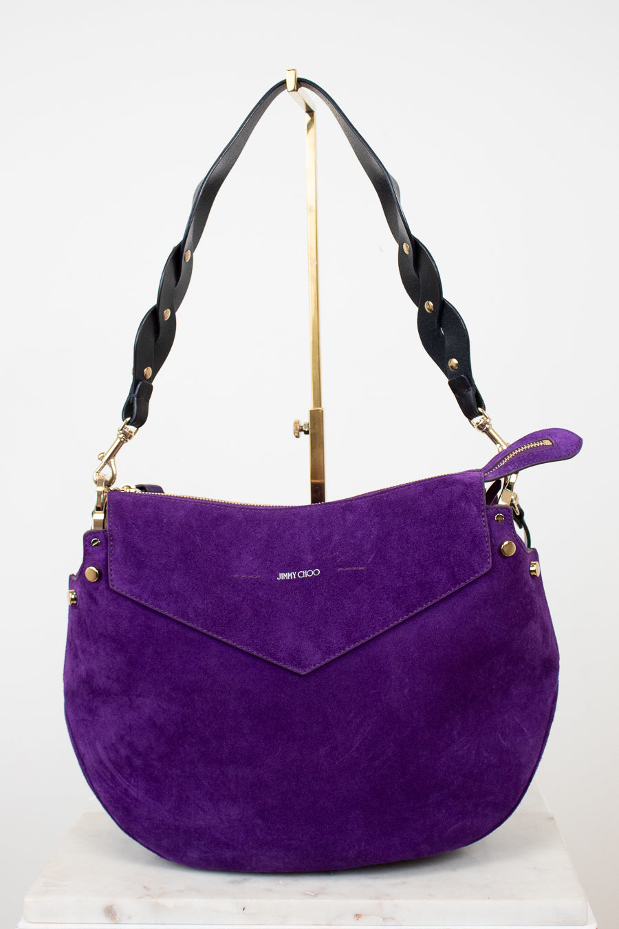 Purple handbag with black handle and gold accents on a white background