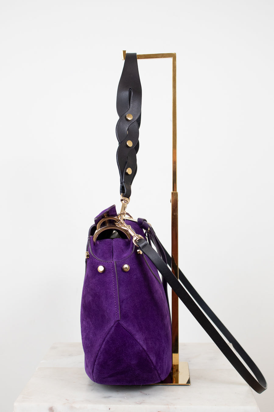 Purple handbag with a black strap on a white background