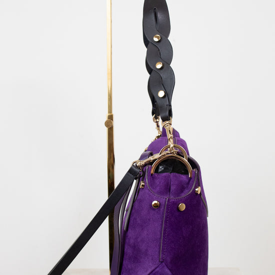 Purple handbag with black strap on a white background