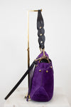 Purple handbag with black strap on a white background