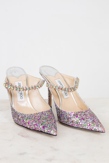 Pair of glittery high-heeled shoes with embellished straps on a light background