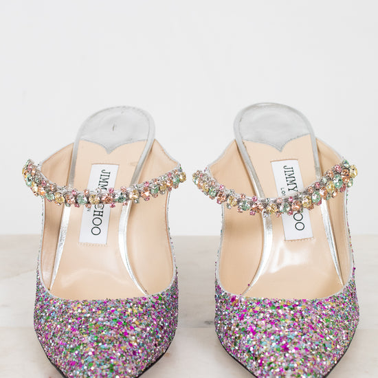 Pair of glittery high-heeled shoes with multicolored embellishments on a light background