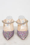 Pair of glittery high-heeled shoes with multicolored embellishments on a light background