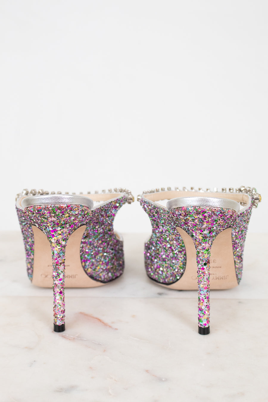 Multicolored glitter high-heeled shoes on a light background