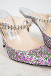 Multicolored glittery high-heeled shoes with 'Jimmy Choo' label on a light background