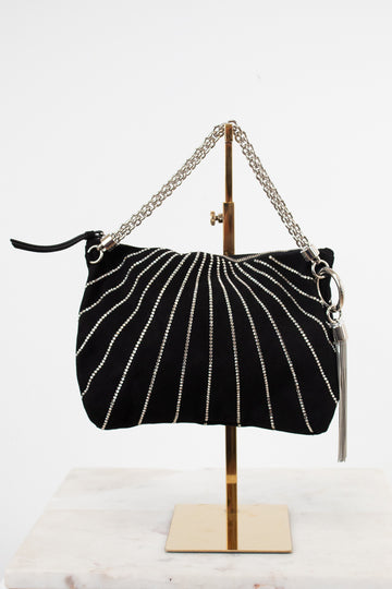A black suede shoulder bag with silver beaded vertical stripes and a silver chain strap, displayed on a gold stand against a white background.