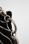Close-up detail of a black handbag featuring a silver-tone metal chain strap, a large interlocking O-ring, and a padlock charm, with the brand name 'Dior' engraved on the ring.