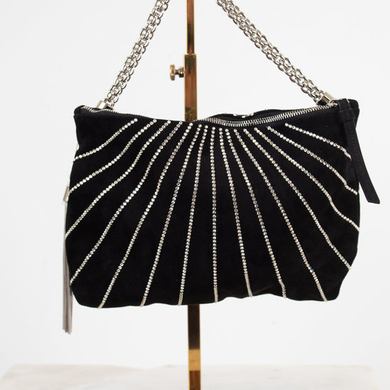 A black velvet shoulder bag with vertical silver rhinestone stripes, displayed on a gold metal stand against a white background.