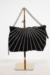 A black velvet shoulder bag with vertical silver rhinestone stripes, displayed on a gold metal stand against a white background.