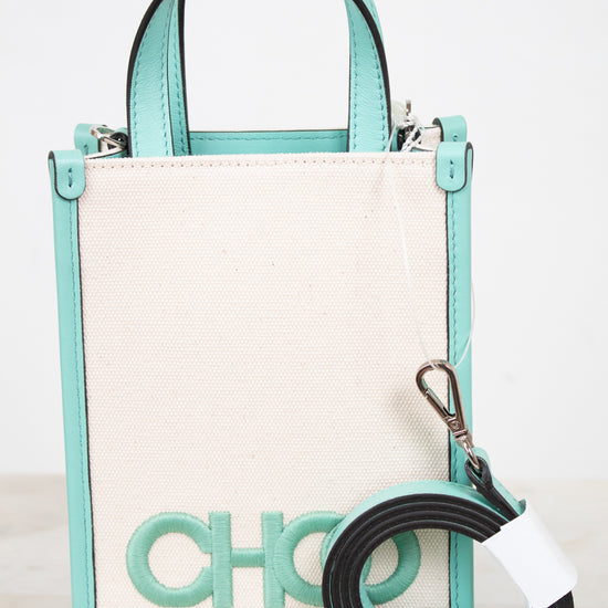 A structured mini tote bag with a cream canvas body and mint green trim, featuring a large 'CHOO' logo on the front and a detachable black and mint green shoulder strap.