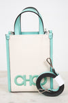 A structured mini tote bag with a cream canvas body and mint green trim, featuring a large 'CHOO' logo on the front and a detachable black and mint green shoulder strap.