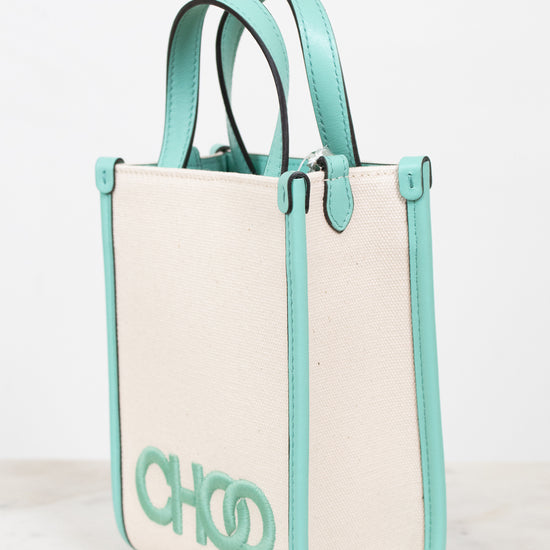 A structured tote bag with a cream canvas body and mint green leather trim, handles, and side borders. The bag features a large mint green 'CHOO' logo on the front, set against a clean white background.