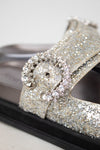 Sandals with silver glittery straps and buckle details on a white background