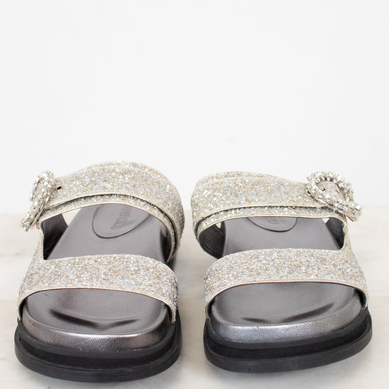 Silver glittery sandals with decorative straps on a white background