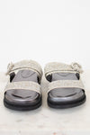 Silver glittery sandals with decorative straps on a white background