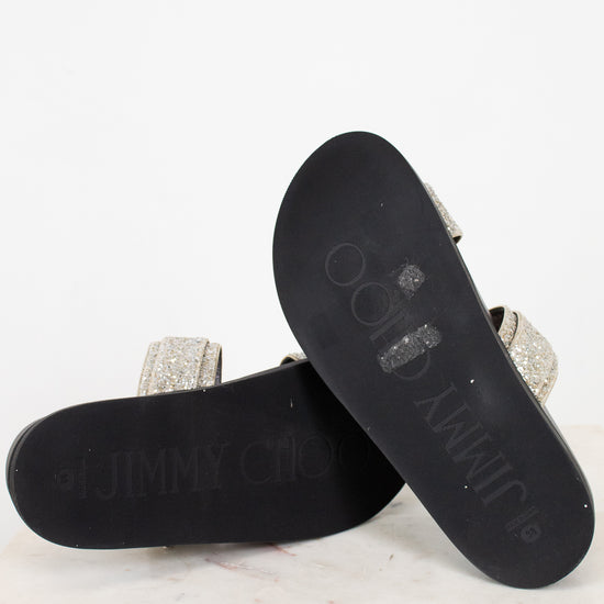 sandals with black soles and glittery straps on a white marble surface
