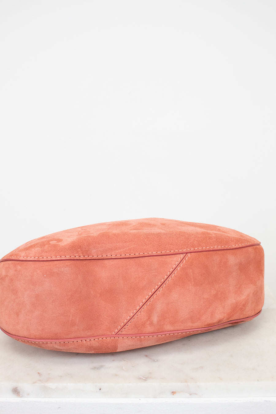 Pink suede bag on a light marble surface