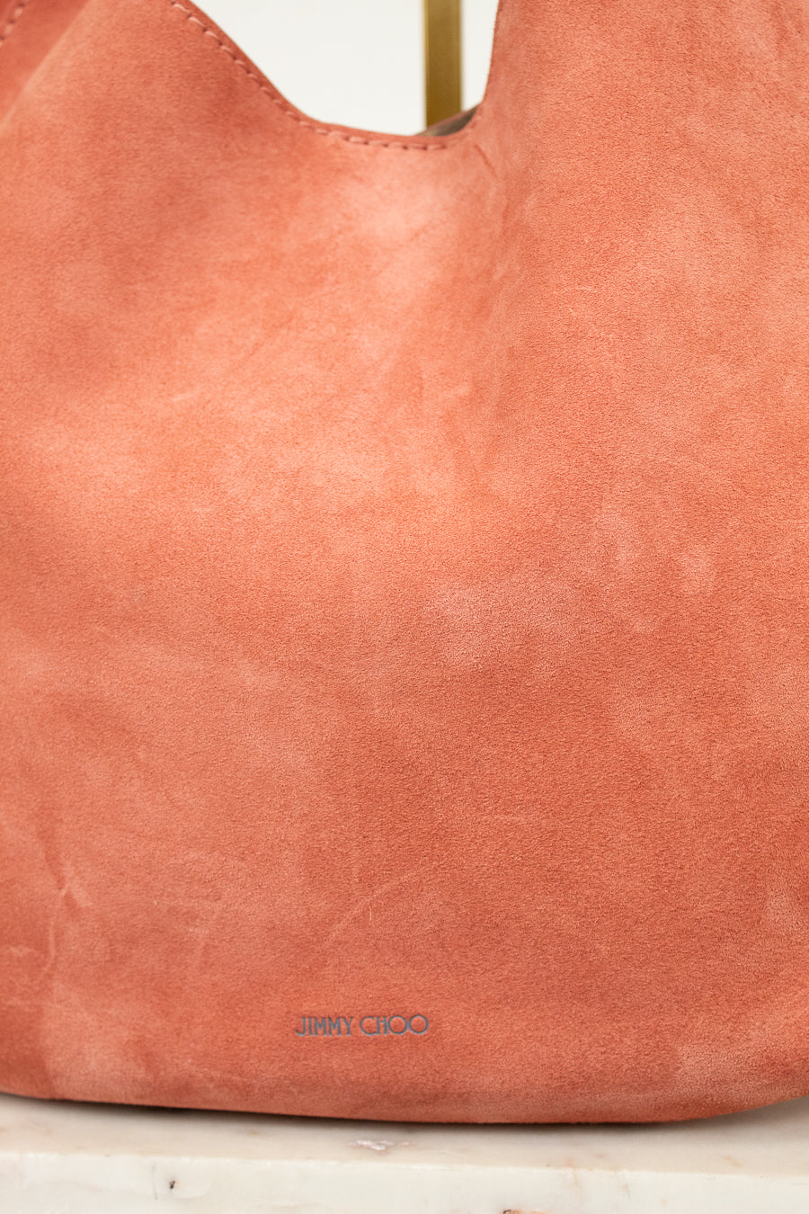 Close-up of a pinkish-brown leather handbag with 'Jimmy Choo' branding.