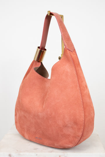 Pink suede handbag with gold accents on a white background