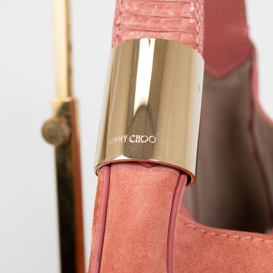 Close-up of a pink handbag with a gold clasp featuring 'Jimmy Choo' branding.